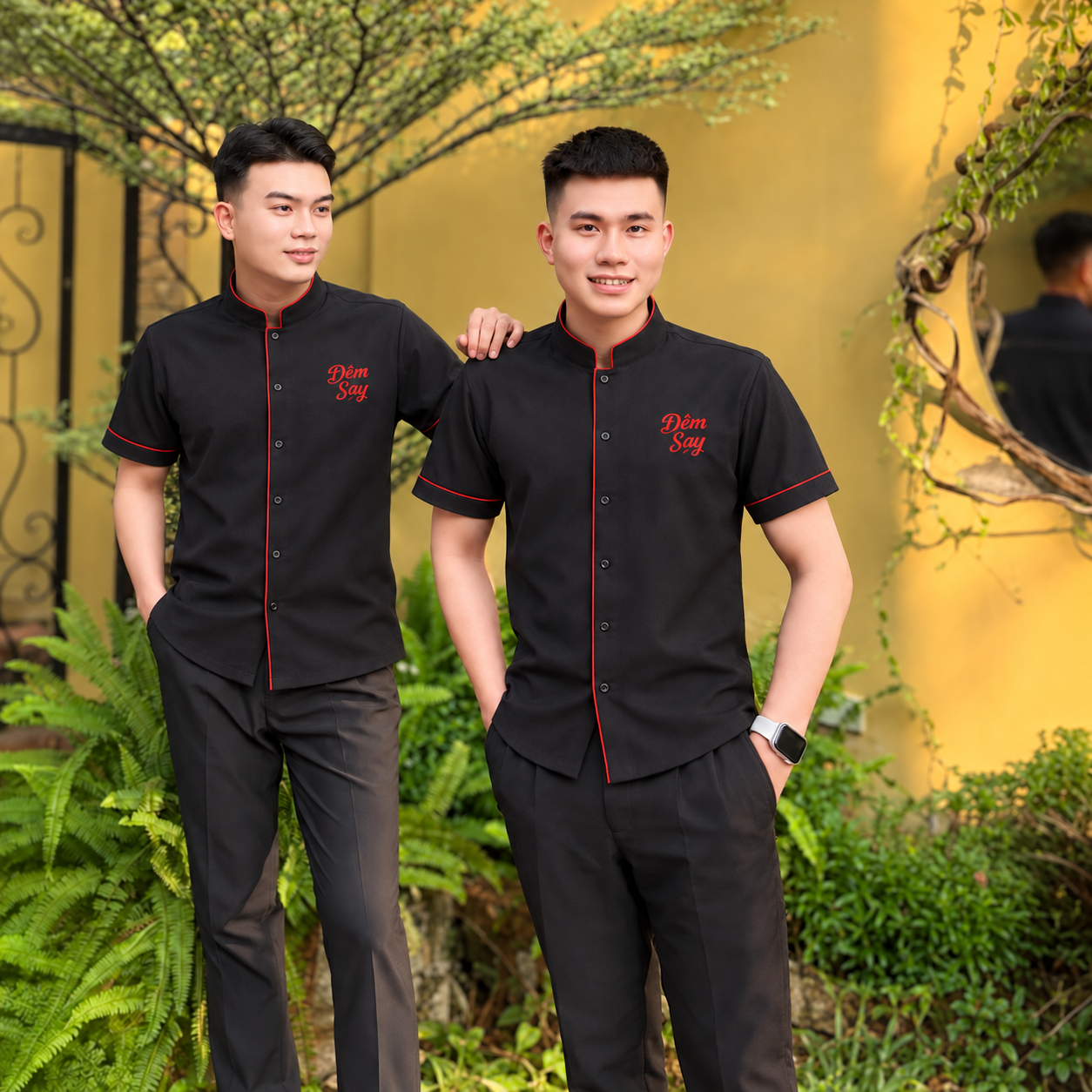 Áo đồng phục cổ trụ đen viền đỏ, tay ngắn, hàng nút trước và chữ Đêm Say trên ngực