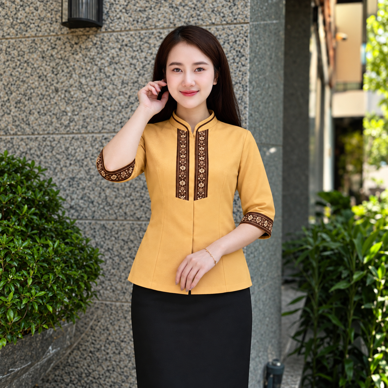 Người mẫu mặc áo đồng phục nữ vàng tay lỡ cổ đứng, thả ngoài chân váy đen