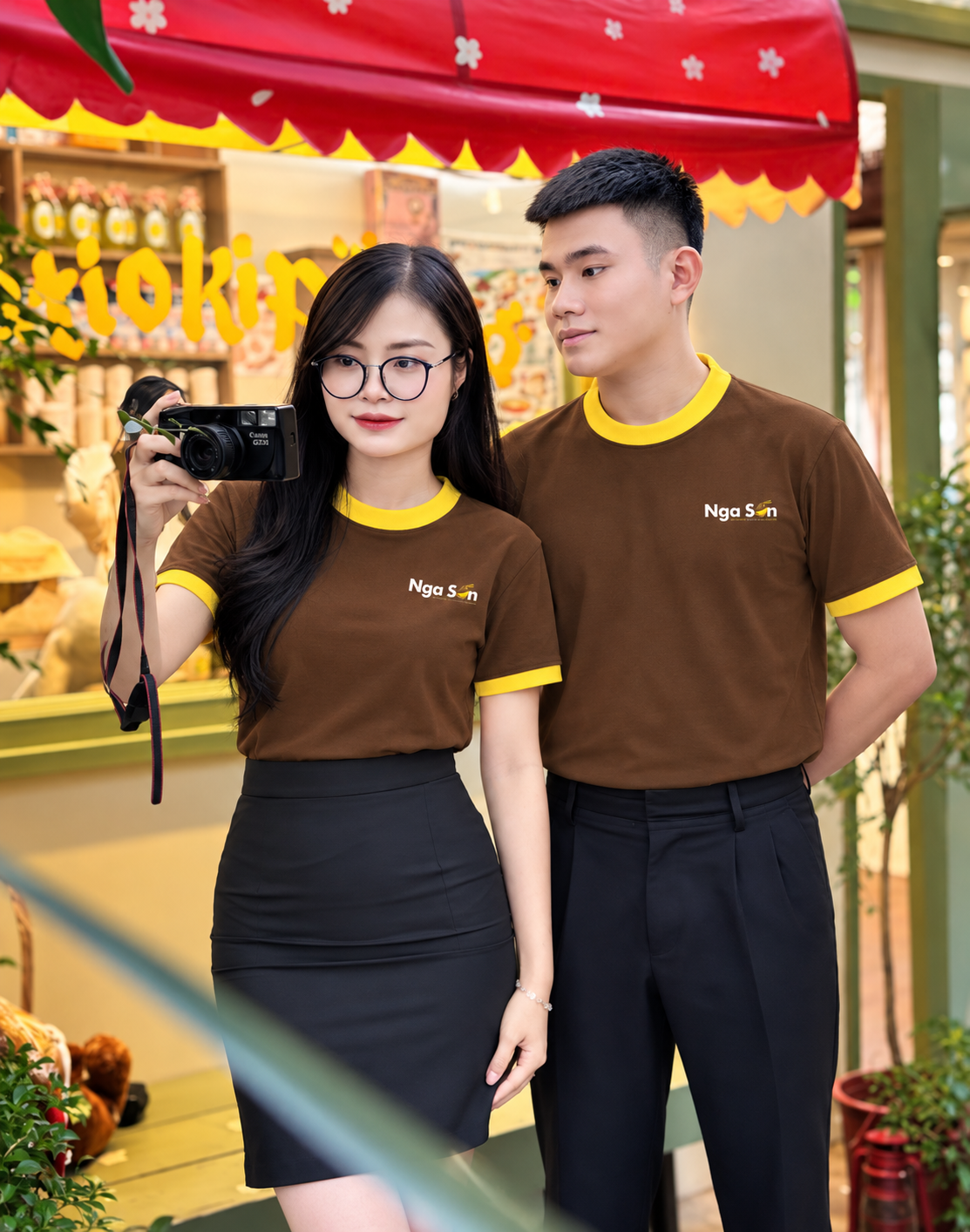 Áo thun cổ tròn đồng phục nhà hàng màu nâu, phối viền vàng ở cổ và tay áo.