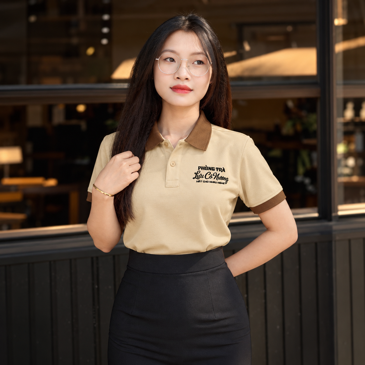 Chi tiết logo màu đen trên áo polo đồng phục quán trà màu kem với thiết kế cổ bẻ màu nâu thanh lịch.